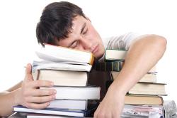 overworked student asleep on top of a pile of homework books